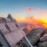 Katahdin Summit Sign with misty sunrise in the background.